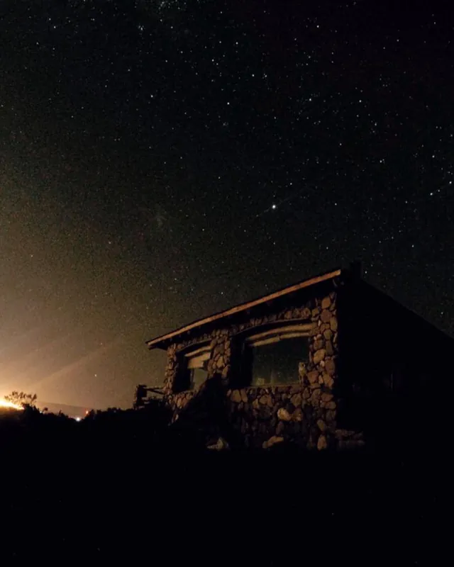 Casa de piedra bajo un cielo lleno de estrellas
