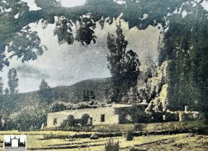 Foto antigua de las construcciones de la estancia entre álamos, con la montaña al fondo
