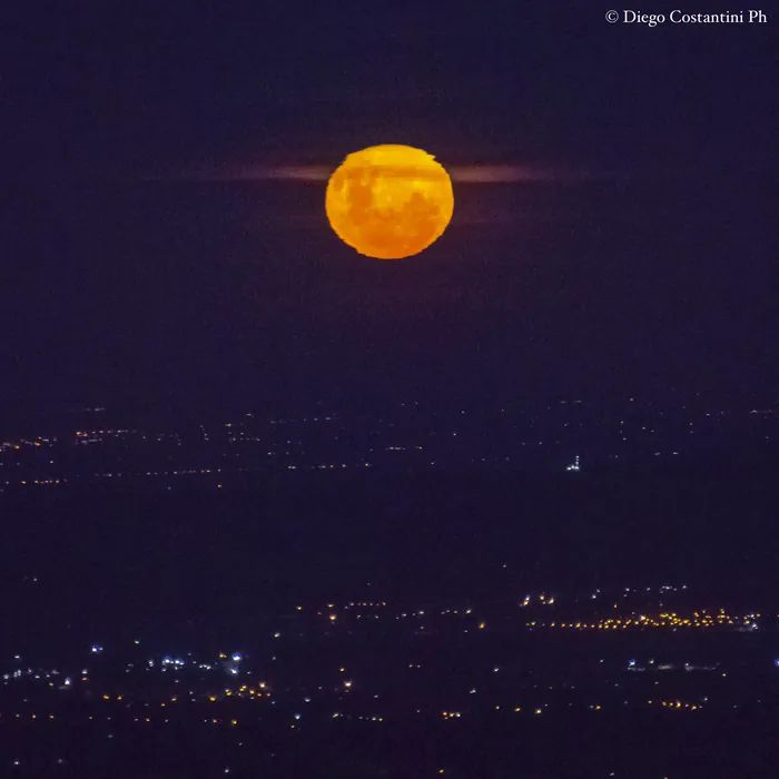 Luna llena saliendo sobre las luces de la ciudad