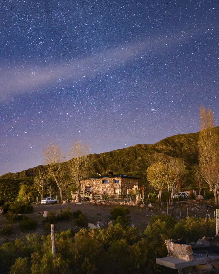 Casa de piedra iluminada bajo un cielo estrellado