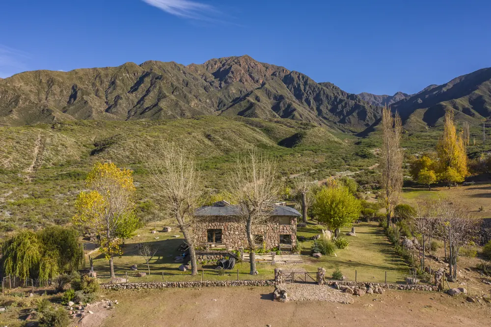 Casa de piedra entre álamos, al pie de la montaña, vista desde el aire