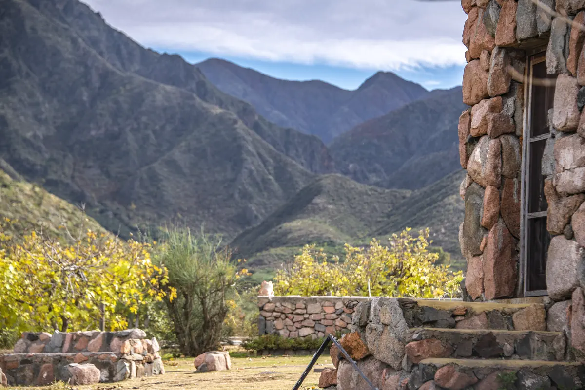 Muro y escalones de piedra de una casa, con vista al valle y la montaña